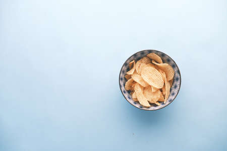 Bowl with tasty potato chips on blue background .の写真素材