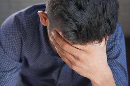 Depressed man feeling sick and worried about financial problemの写真素材