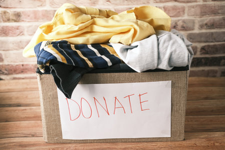 Donation box with donation clothes on a wooden table .の写真素材