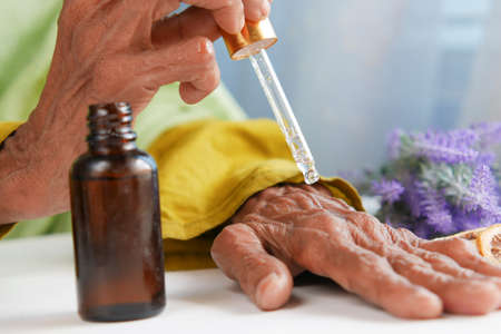 senior women applying essential oils on handの写真素材