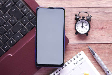 smart phone with empty screen, laptop on wooden backgroundの写真素材