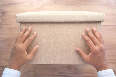 young man hand hold a box against yellow backgroundの写真素材