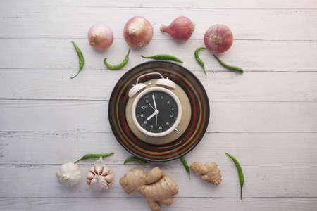 fresh vegetables and alarm clock on heart shape plate on tableの写真素材