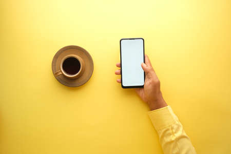 high angle view of me hand using smart phone and drinking coffeeの写真素材