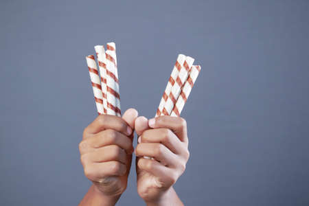 hand hold wafer roll chocolate against gray backgroundの写真素材