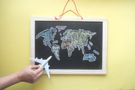 travel concept with hand hold a airplane on world map drown on chalk boardの写真素材