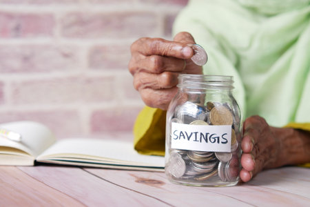 senior women saving coins in a jar white sitedの写真素材