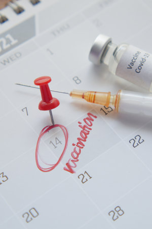 vaccine day concept glass ampoule with vaccine and syringe on calendarの写真素材