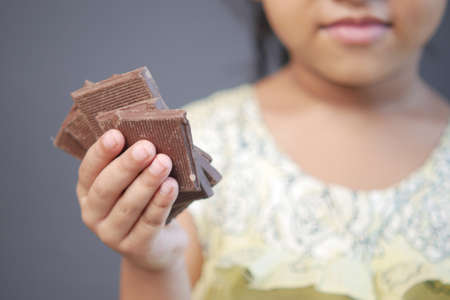 child girl hand pick dark chocolate against gray backgroundの写真素材