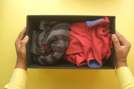 Donation box with donation clothes on a wooden table .の写真素材