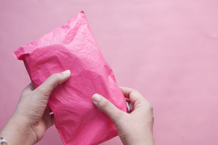 holding pink color paper bubble envelope on tableの写真素材