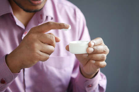 man applying beauty cream onto skinの写真素材