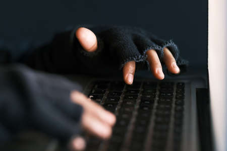 hacker hand stealing data from laptop top downの写真素材