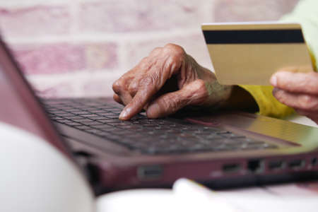 senior women holding credit card and using laptop shopping onlineの写真素材