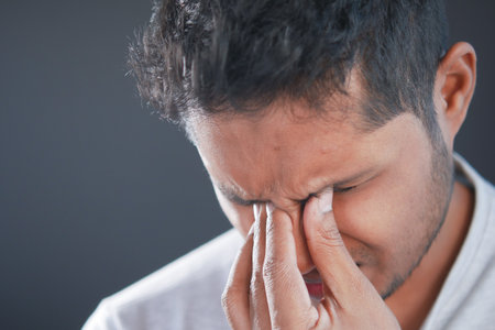 Close up of upset man suffering from strong eye painの写真素材