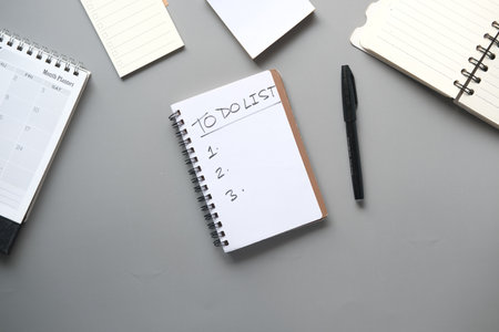 To do list in notebook with office suppliers on desk.の写真素材