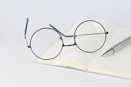 notepad, eyeglass and a pencil on wooden tableの写真素材
