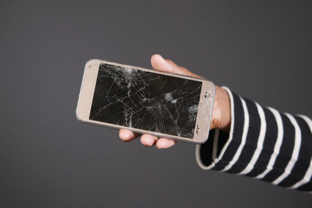 Close up of man hand holding broken smart phone.の写真素材