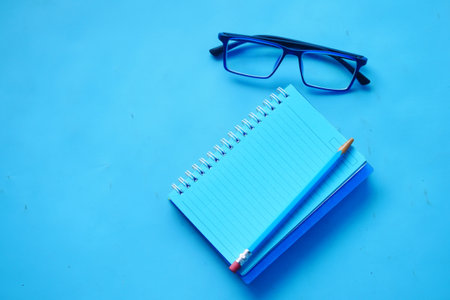 high angle view of blue color notepad with pencil on blue deskの写真素材
