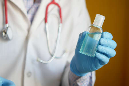 close up of doctor hand in latex gloves holding hand sanitizerの写真素材