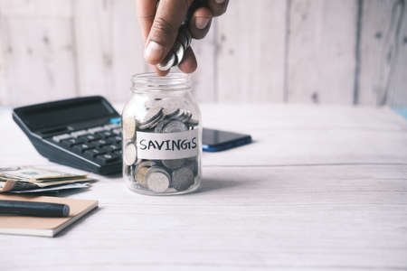 young man saving coins in a jar white sitedの写真素材