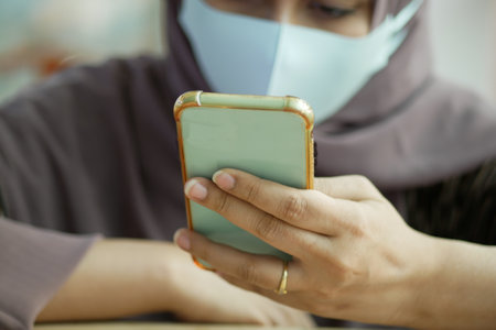 young women with face mask using smart phone at cafeの写真素材