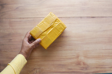 hand holding a yellow color deliver packet on tableの写真素材
