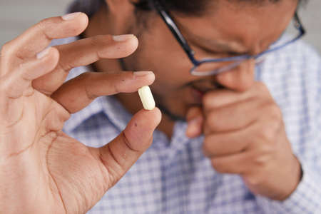 sick man hand holding medical pillsの写真素材