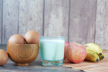 eggs in a bow and a glass of milk on tableの写真素材