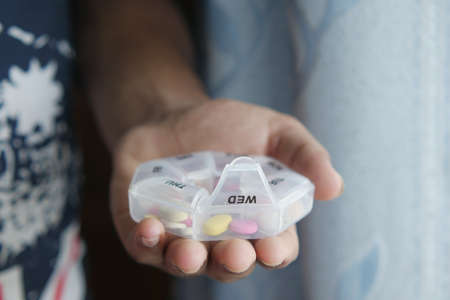 mans hands taking medicine from a pill boxの写真素材