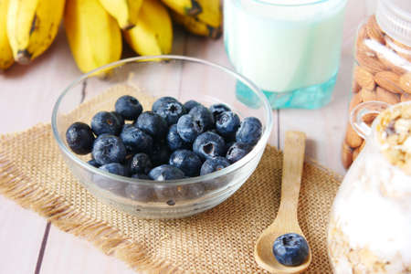 fresh blue berry in bowl with banana, milk and almond on tableの写真素材