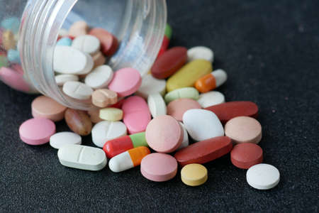 Close up of many colorful pills and capsules on black backgroundの写真素材