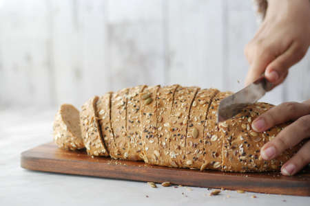 Women hand cutting baked brow bread on table.の写真素材