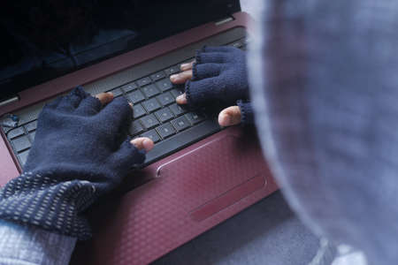 rear view of hacker hand stealing data from laptop top downの写真素材