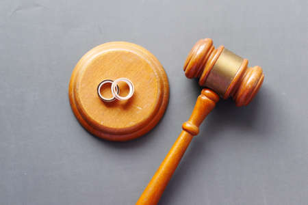 Divorce concept with gavel and wedding rings on table.の写真素材