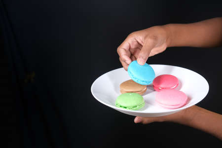 hand pick macaroon on blue background with copy spaceの写真素材
