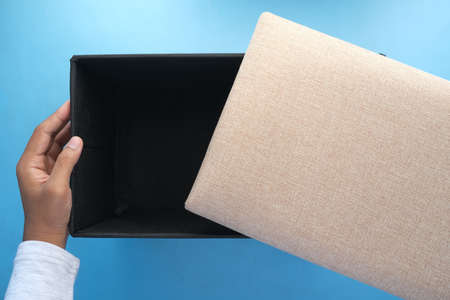 young man hand hold a box against yellow backgroundの写真素材