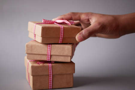 child hand hold homemade gift box against gray backgroundの写真素材