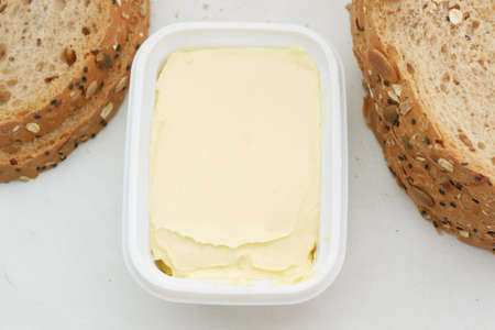 fresh butter in a container with bread on white backgroundの写真素材