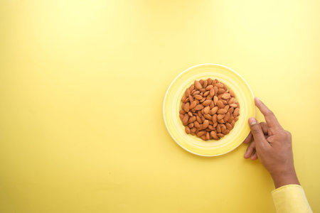 top view of almond on a plate on yellow background