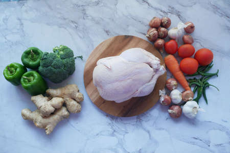 raw whole chicken and vegetables on tiles backgroundの写真素材