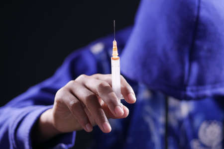 drug addiction concept with hand holding syringe isolated on blackの写真素材