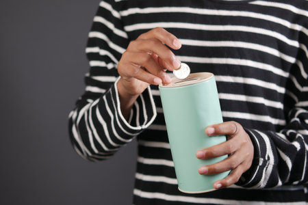 young man saving coins in a jar white sitedの写真素材