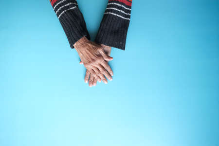 top view of hands of a elderly person on blue backgroundの写真素材
