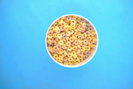 top view of colorful cereal corn flakes in a bowl on blue backgroundの写真素材