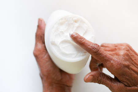 senior woman applying beauty cream onto skinの写真素材