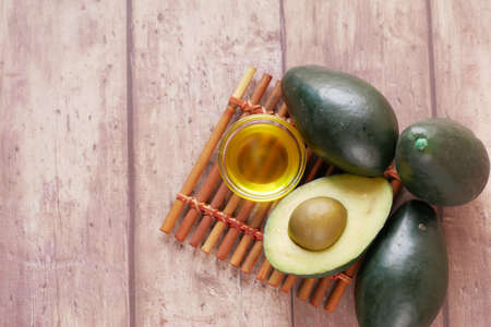 oil and slice of avocado on wooden tableの写真素材