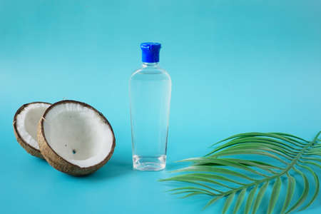 slice of fresh coconut and bottle of oil on blue backgroundの写真素材