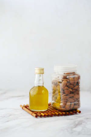 Almond oil in bottle and nuts on white background.の写真素材