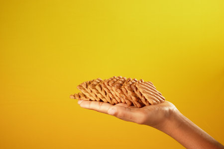 close up of holding sweet cookies against yellow backgroundの写真素材
